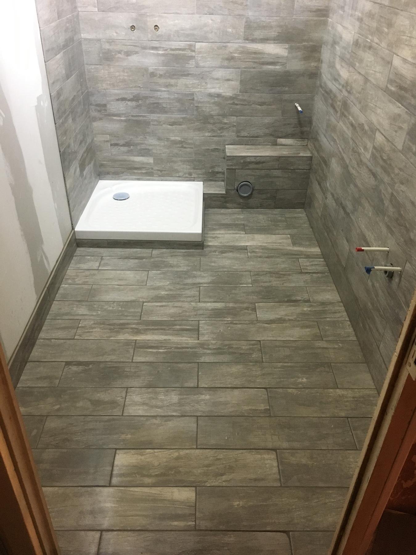 Salle d'eau carrelée en imitation bois avec receveur de douche et banquette, réalisée par CEDIEY dans le Var